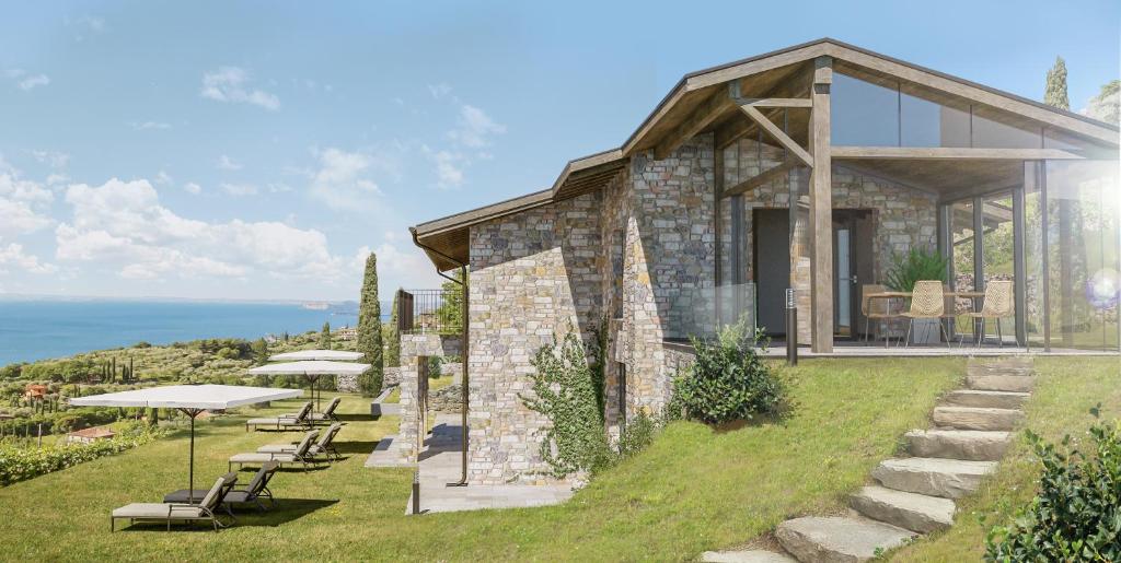 una casa de piedra en una colina con sillas y mesas en Colago Private Villas Lake Garda, en Toscolano Maderno