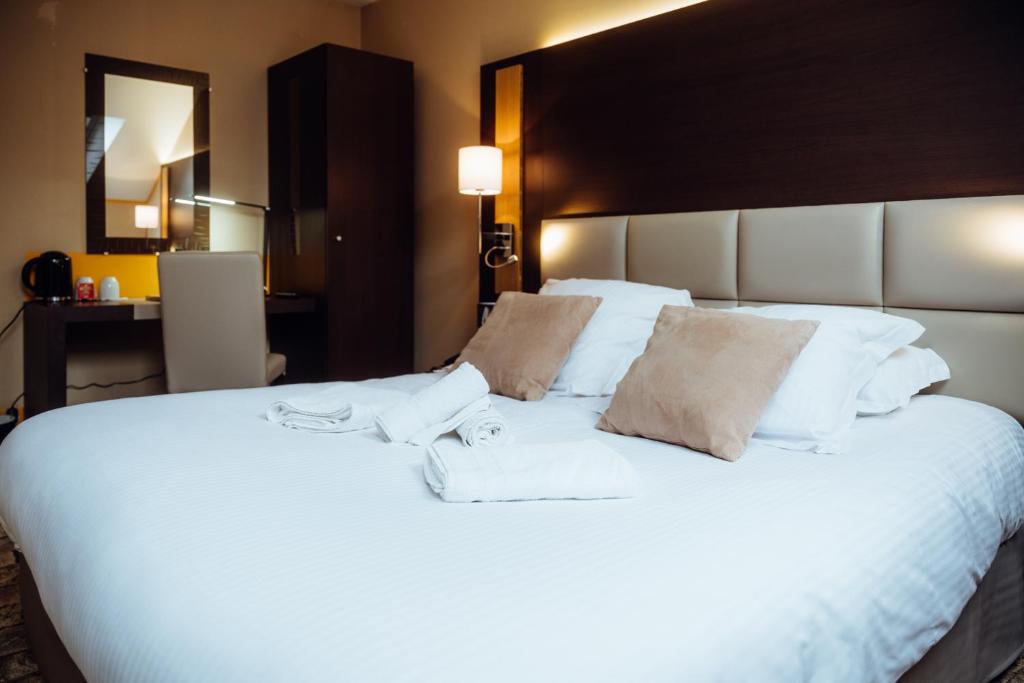 a large white bed with two towels on it at Hotel Le Dauphin in Honfleur