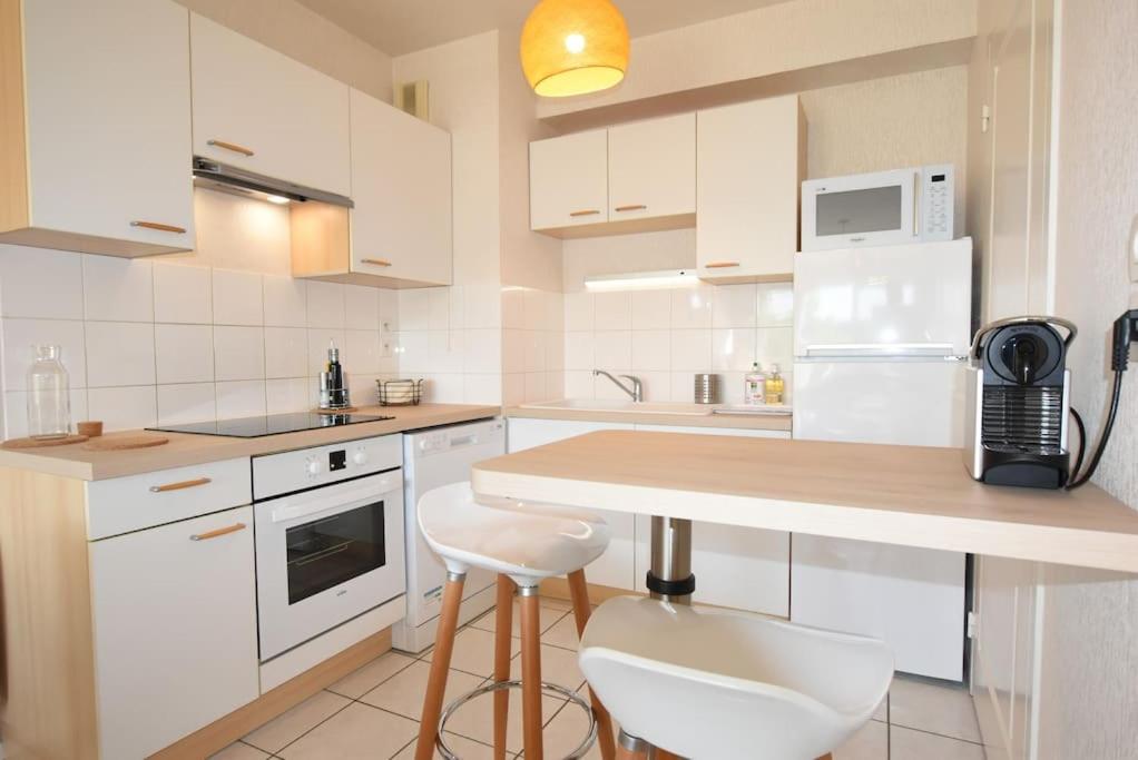 a kitchen with white cabinets and a counter with stools at Le Maginot, 1 chambre, garage, terrasse in Rennes