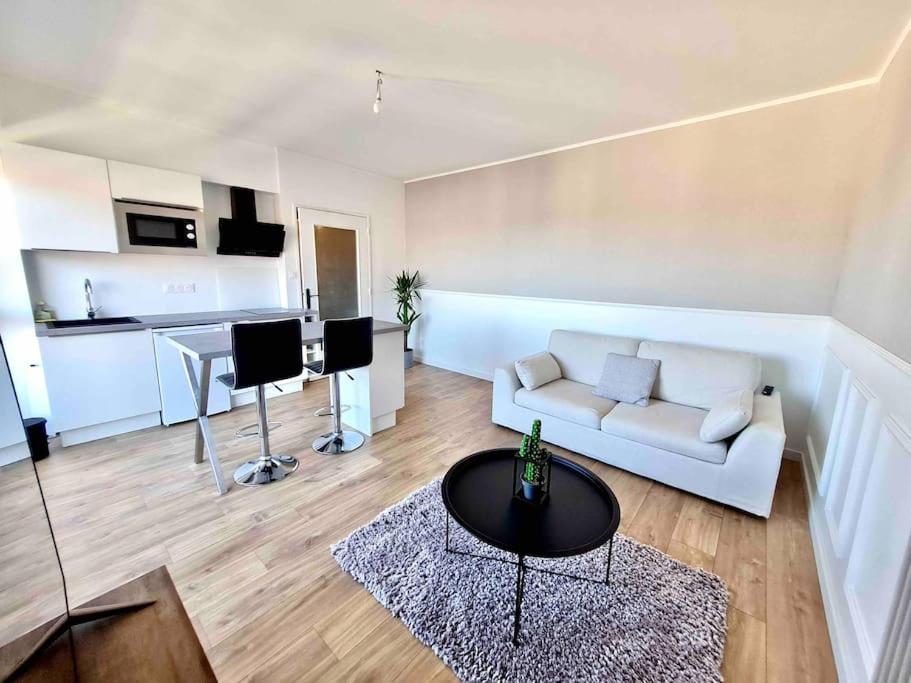 ein Wohnzimmer mit einem weißen Sofa und einem Tisch in der Unterkunft Superbe appartement in Pau