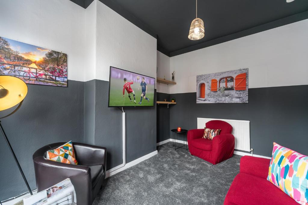 a living room with a red couch and a tv at 3 bedroom Shalom Sleeps 5 - Ideally Located in Hull- 2 Mins walk to Vibrant Newland Ave in Hull
