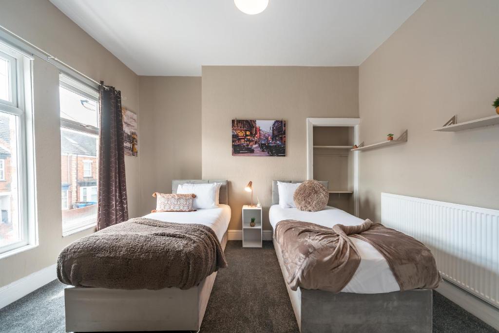 a bedroom with two beds and a window at 3 bedroom Shalom Sleeps 5 - Ideally Located in Hull- 2 Mins walk to Vibrant Newland Ave in Hull