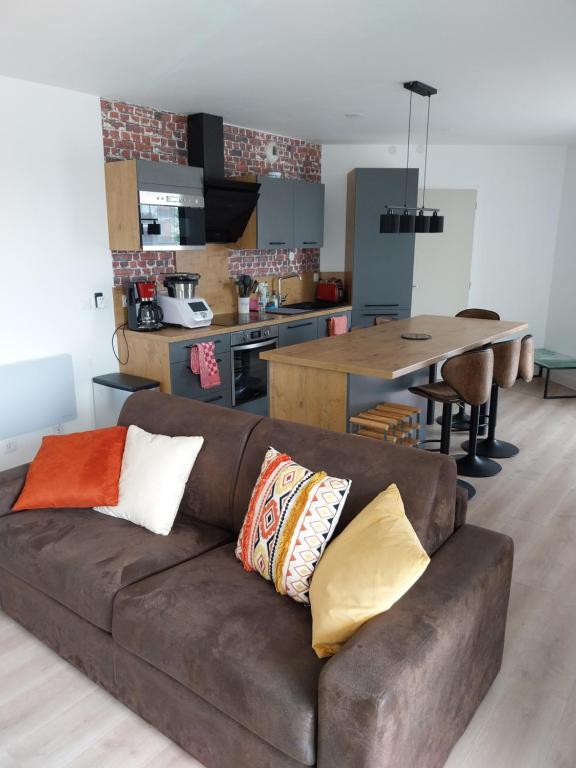 una sala de estar con un sofá marrón con almohadas. en Confort au pied du tram en Burdeos