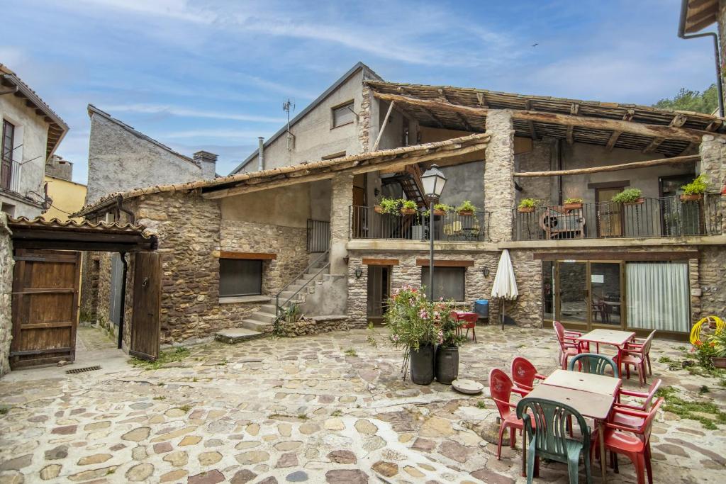 a stone house with a patio with tables and chairs at Mossen Batista Freixe in Les Iglésies