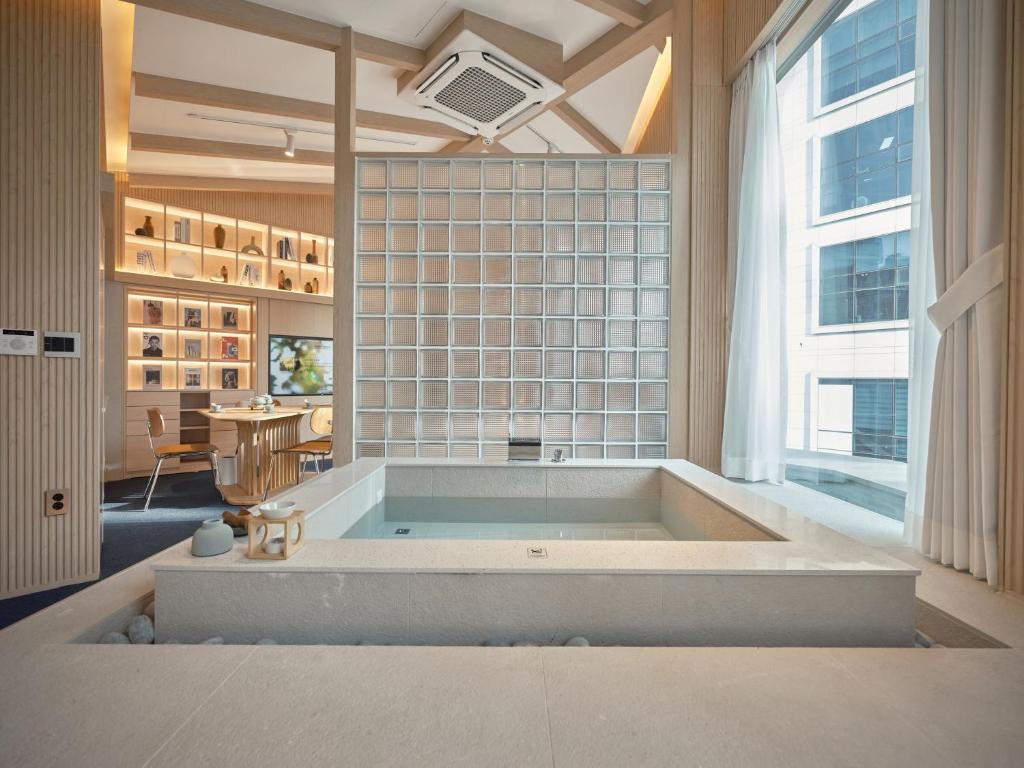 bañera grande en una habitación con ventana grande en UH Suite Seoul Square en Seúl