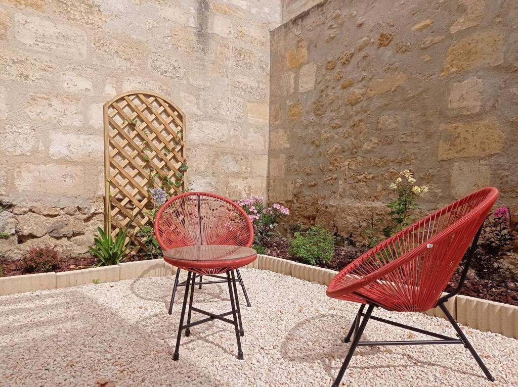 zwei rote Stühle neben einer Steinmauer in der Unterkunft Joli appartement avec jardin / Vieux-Lormont in Lormont