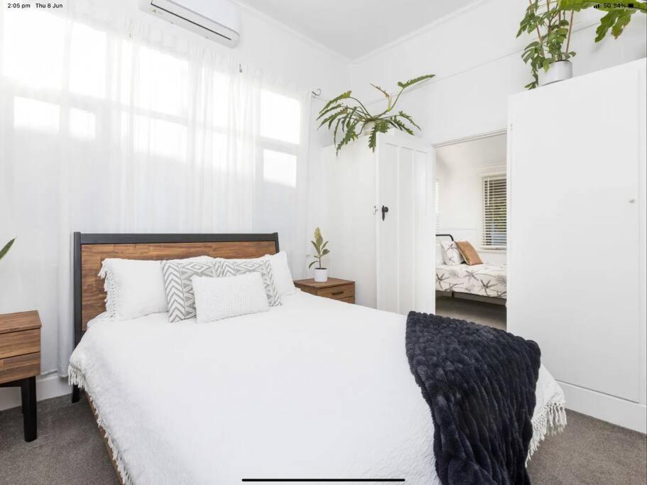 a white bedroom with a large bed with white walls at Walnut Cottage in Mildura
