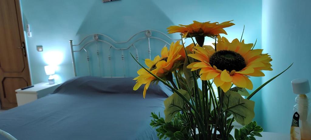 eine Vase voller Sonnenblumen neben einem Bett in der Unterkunft Il Girasole in Rutigliano