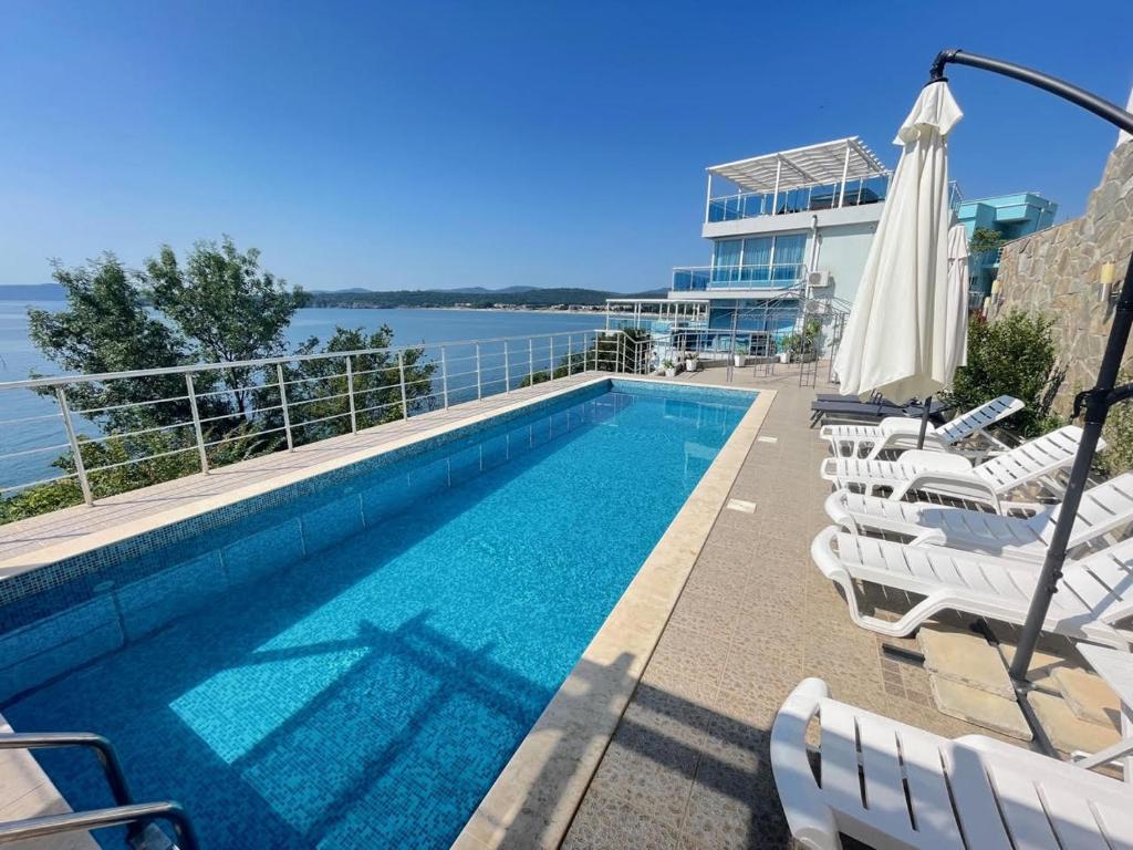 een zwembad met stoelen en een parasol bij Villa Mare Blu in Sozopol