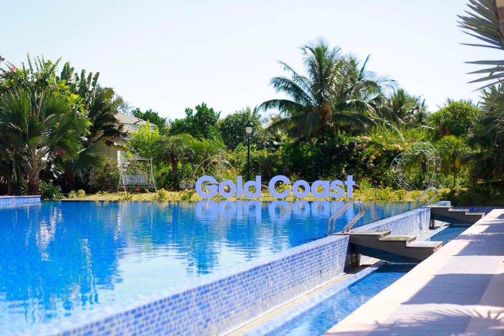 a swimming pool with blue water and palm trees at Gold Coast Hotel Resort & Spa in Dong Hoi