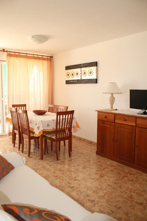 uma sala de estar com uma mesa e cadeiras e uma televisão em Apartamento vacacional Jávea em Xàbia