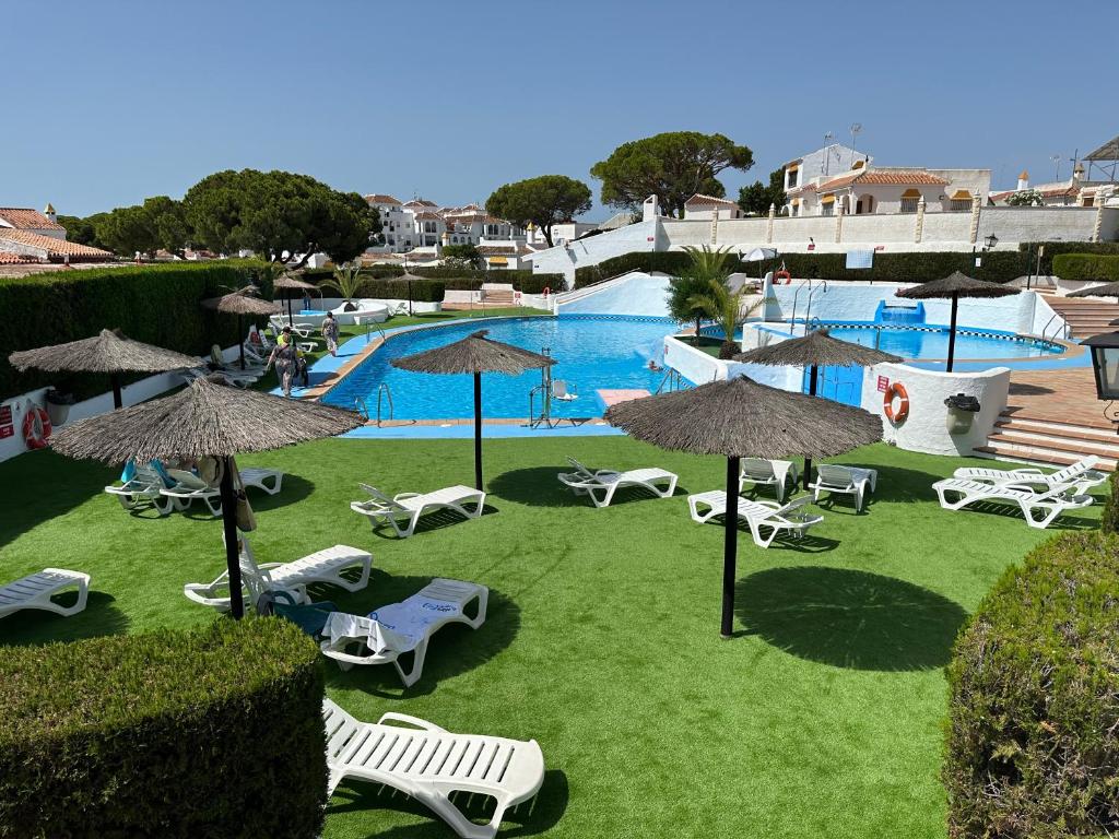 a view of a pool with chairs and umbrellas at Residencial Macarena in Matalascañas