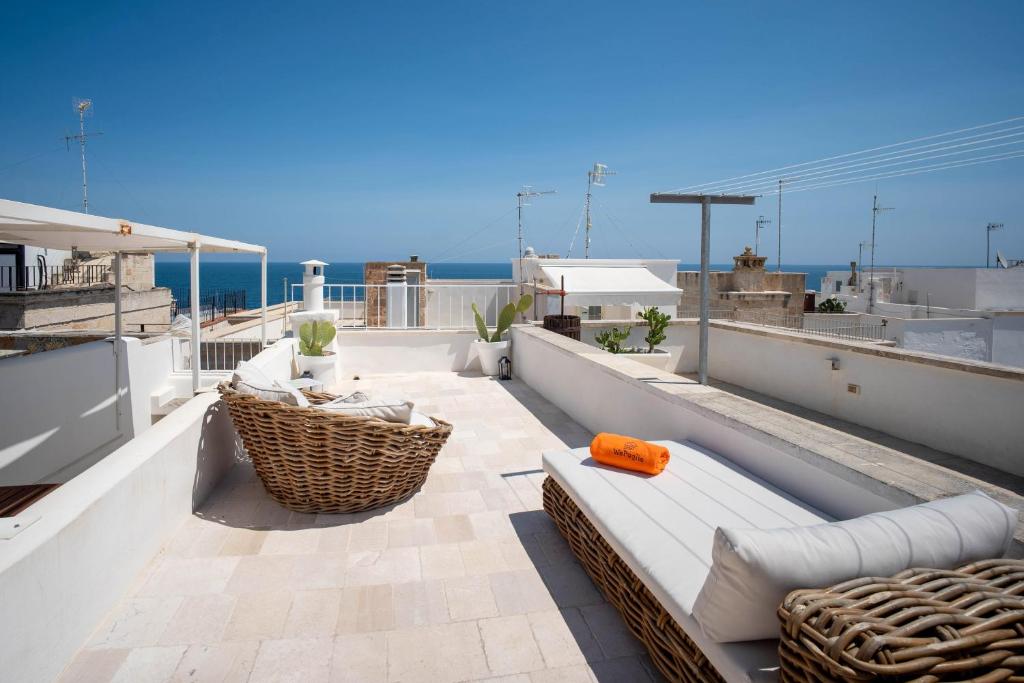 een balkon met een bank en stoelen op een dak bij WePuglia - Dimora Elia in Polignano a Mare