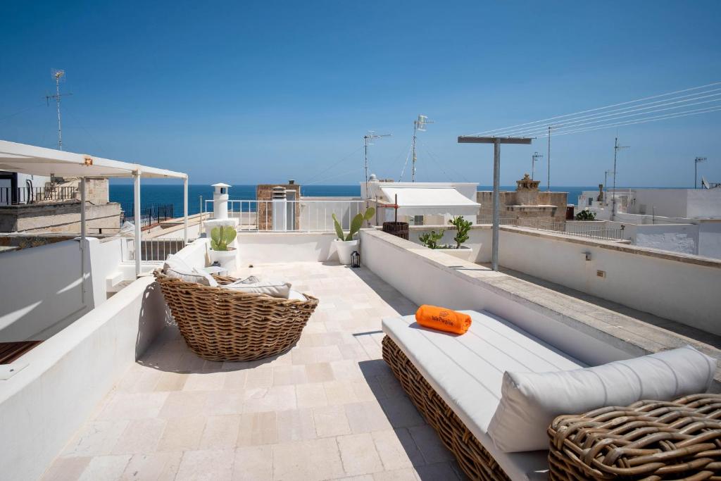 a balcony with a couch and chairs on a roof at WePuglia - Dimora Elia in Polignano a Mare