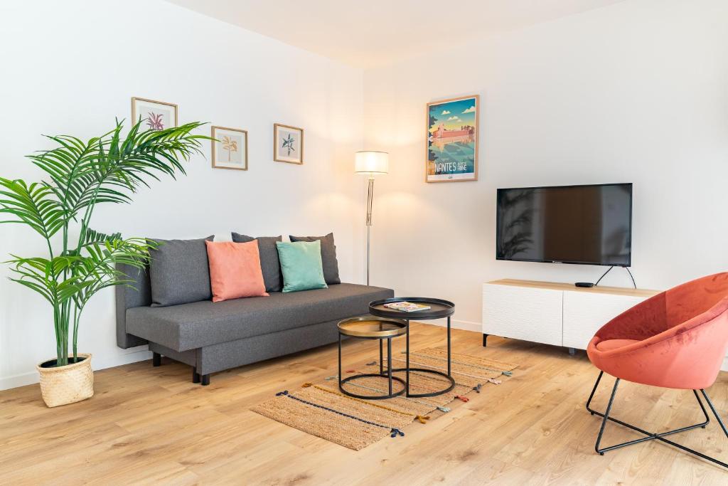 un salon avec un canapé et une télévision dans l'établissement Le Congrès- Au cœur du centre ville avec Parking, à Nantes