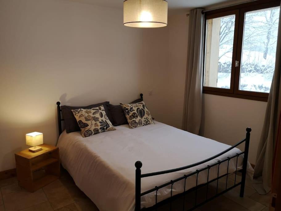 a bedroom with a bed with a lamp and a window at APPARTEMENT DANS CHALET 6 PERSONNES in Vallouise