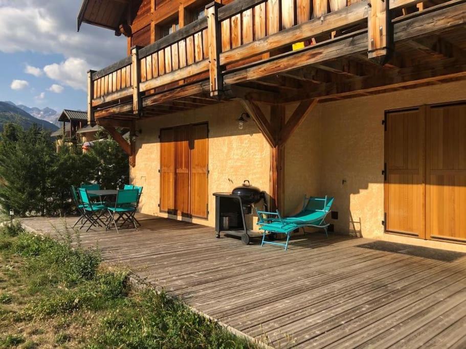 a deck with chairs and a grill on a house at APPARTEMENT DANS CHALET 6 PERSONNES in Vallouise
