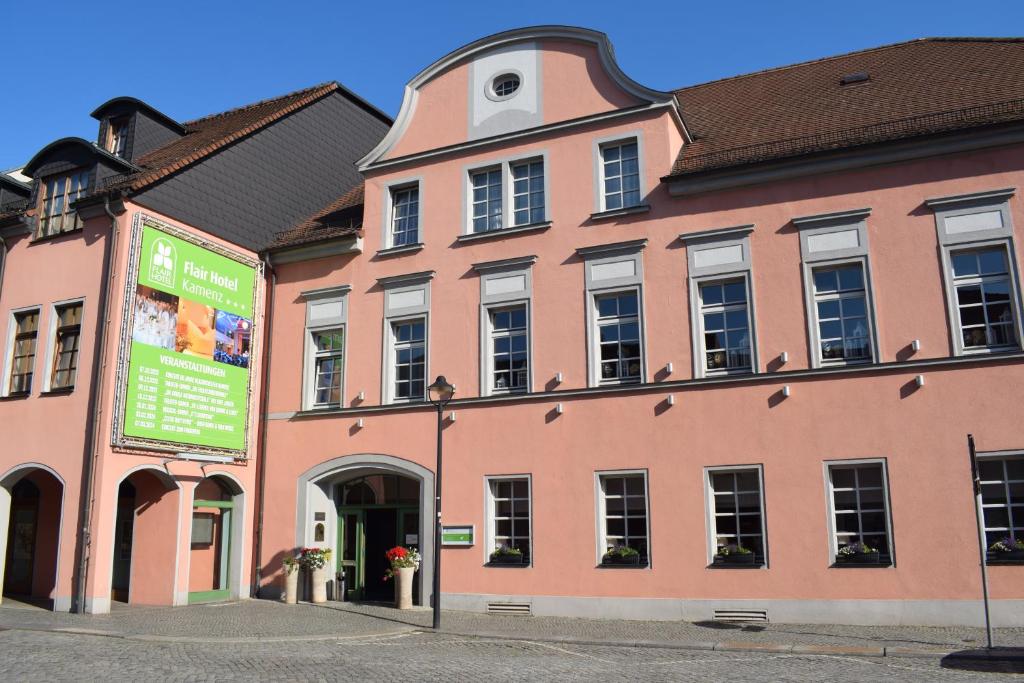 a large pink building with a sign in front of it at Flair Hotel Kamenz in Kamenz