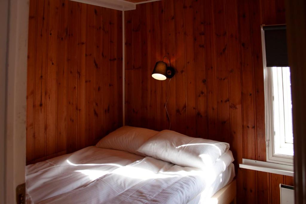 a bed in a room with a wooden wall at Authentic central located cabin close to Reinebringen Lofoten in Reine