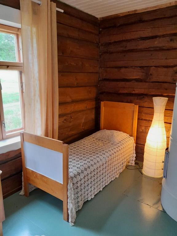 1 dormitorio con 1 cama en una habitación con paredes de madera en Cozy cottage by the lake, en Lohja
