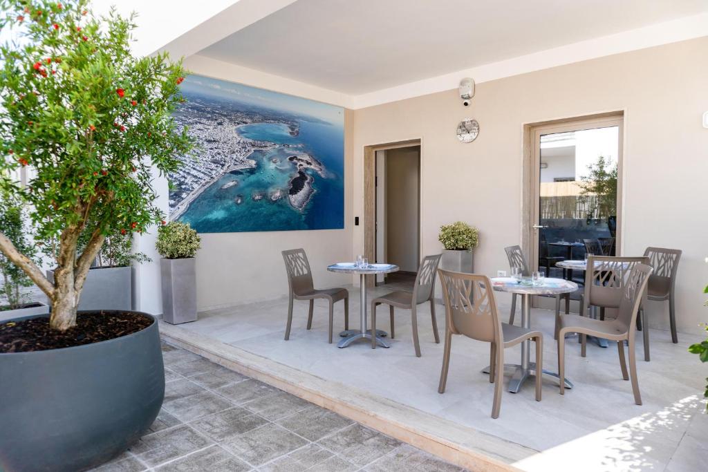 a patio with tables and chairs and a tree at Cinque Venti BB Porto Cesareo in Porto Cesareo