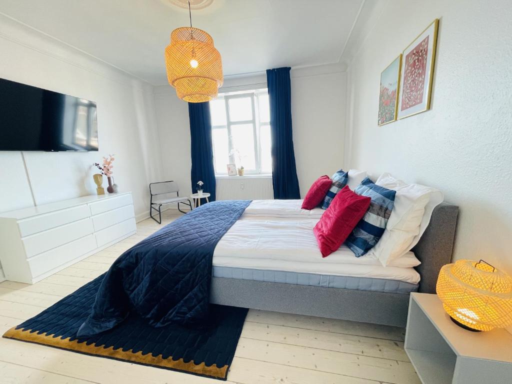 1 dormitorio con 1 cama grande con almohadas rojas y azules en aday - Ocean Shores central Apartment, en Frederikshavn