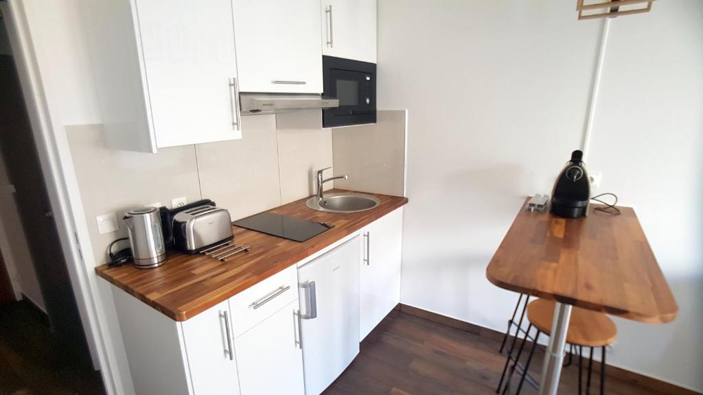 a small kitchen with white cabinets and a sink at Babylone 1 in Le Pré-Saint-Gervais