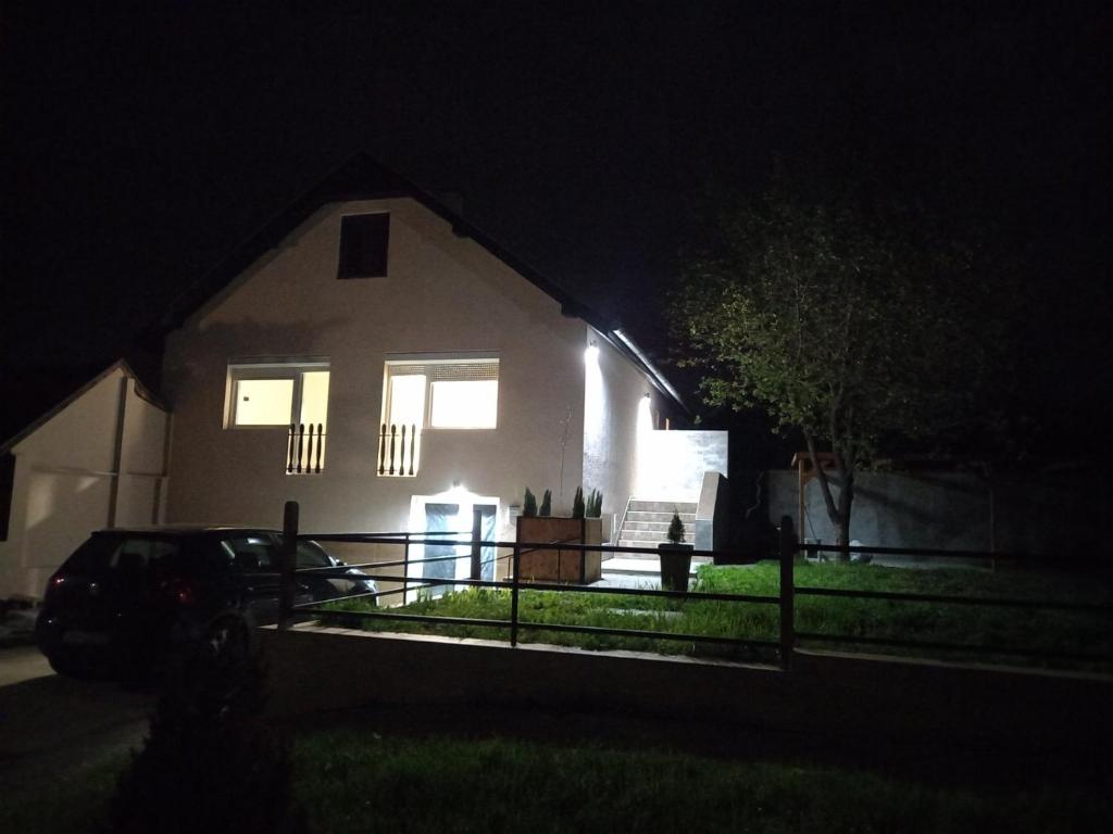 une maison blanche la nuit avec une voiture garée devant dans l'établissement APARTMANI JORGIĆ, à Pačir