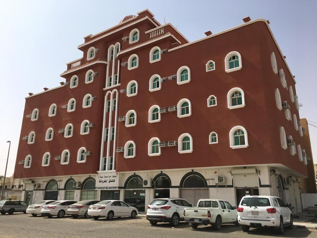 un grand bâtiment rouge avec des voitures garées devant lui dans l'établissement الراحة بلازا للشقق المفروشة, à Sharurah