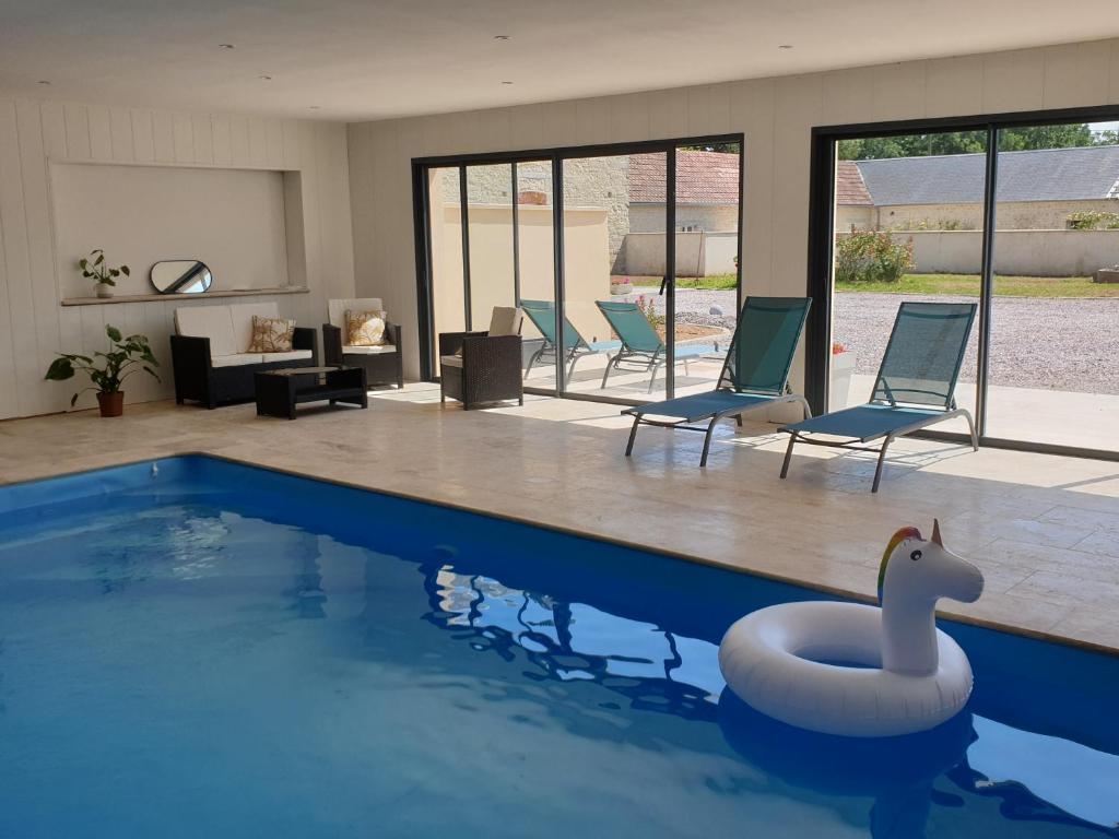 una piscina con sillas y un cisne en el agua en Ferme de Barville & SPA, en Écrammeville
