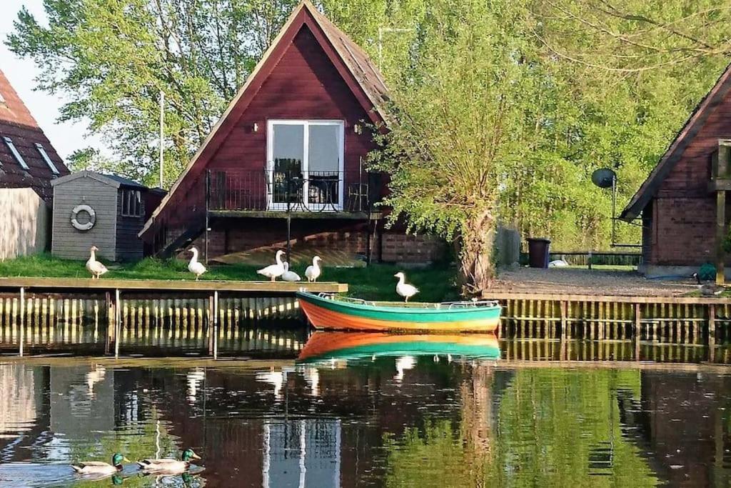 um barco na água em frente a uma casa em River Lark Lodge em Ely