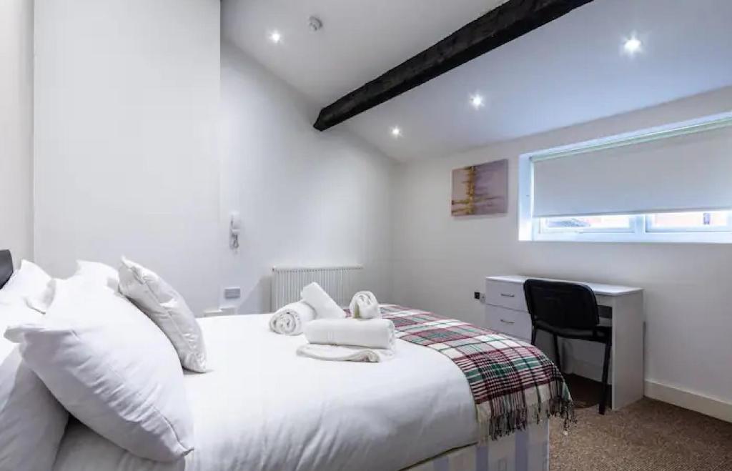 um quarto com uma cama branca, uma secretária e uma janela. em Kelvin Grove by UStay em Liverpool