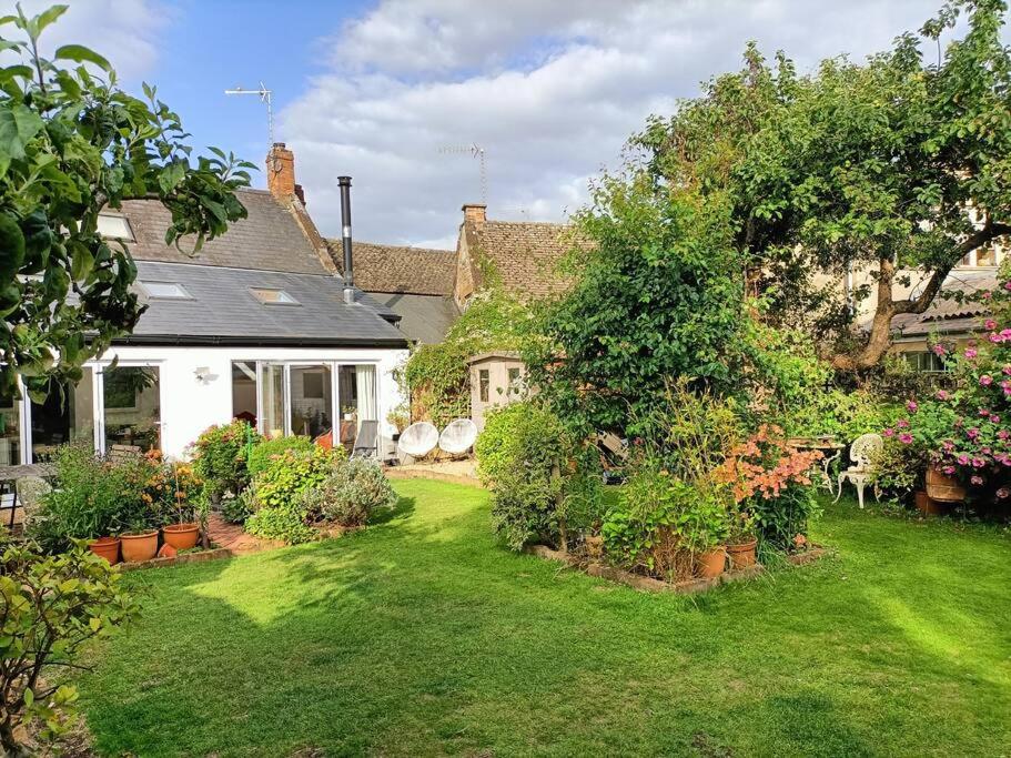 a house with a yard with flowers and plants at Cybil's Retreat - Renovated 2 bedroom house with enclosed garden in Uppingham