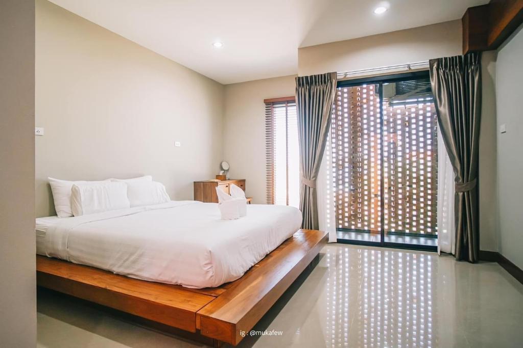 a bedroom with a bed and a large window at Na Sukhothai Hotel in Sukhothai