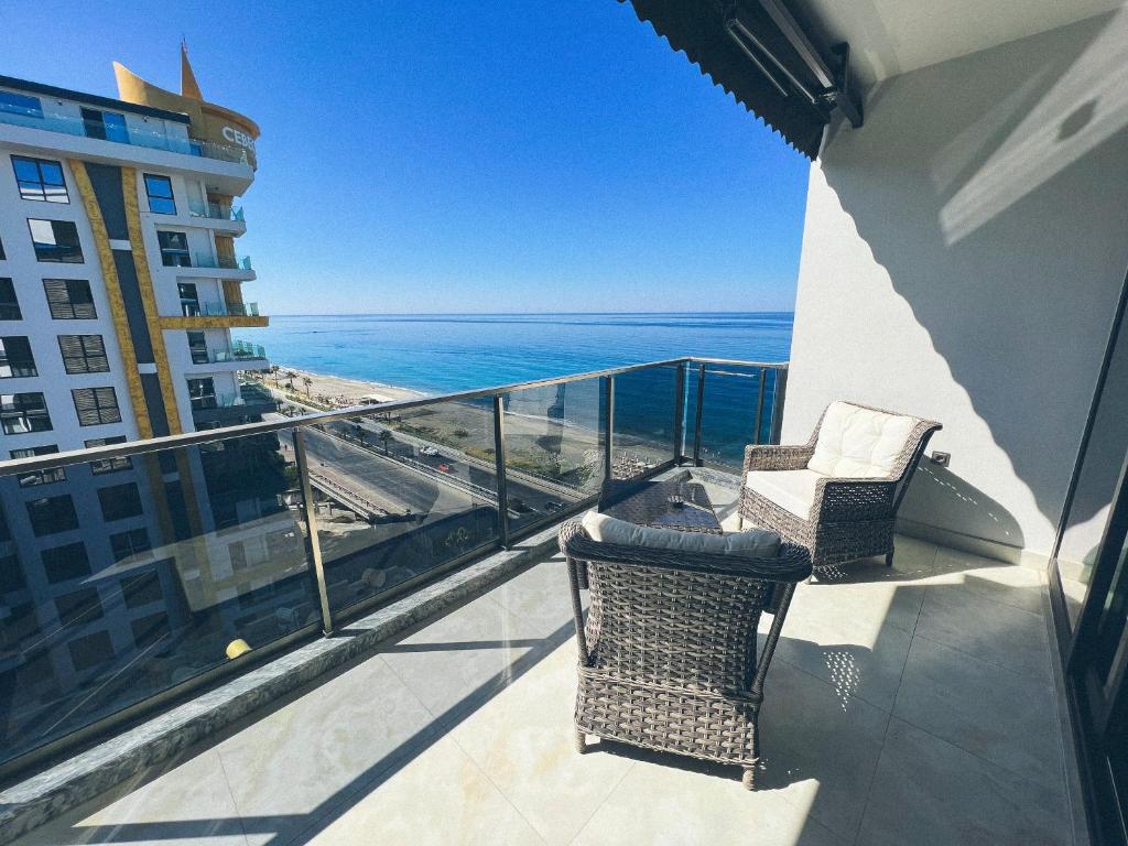 a balcony with two chairs and a view of the ocean at Traumhaftes Apartment mit Privatstrand, Sea View, Pool, Sauna, Gym, Playground in erster Reihe, Alanya-Mahmutlar in Alanya