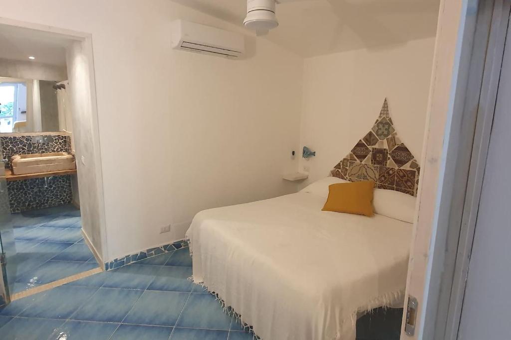 a bedroom with a white bed with a yellow pillow at Marbnb Appartamenti Ponza centro, Porto Appartamento Ponza in Ponza