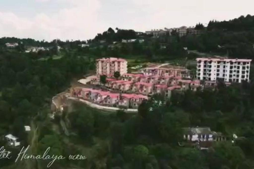 a large pink building in the middle of a city at Nilay himalayan homestay in Rānīkhet