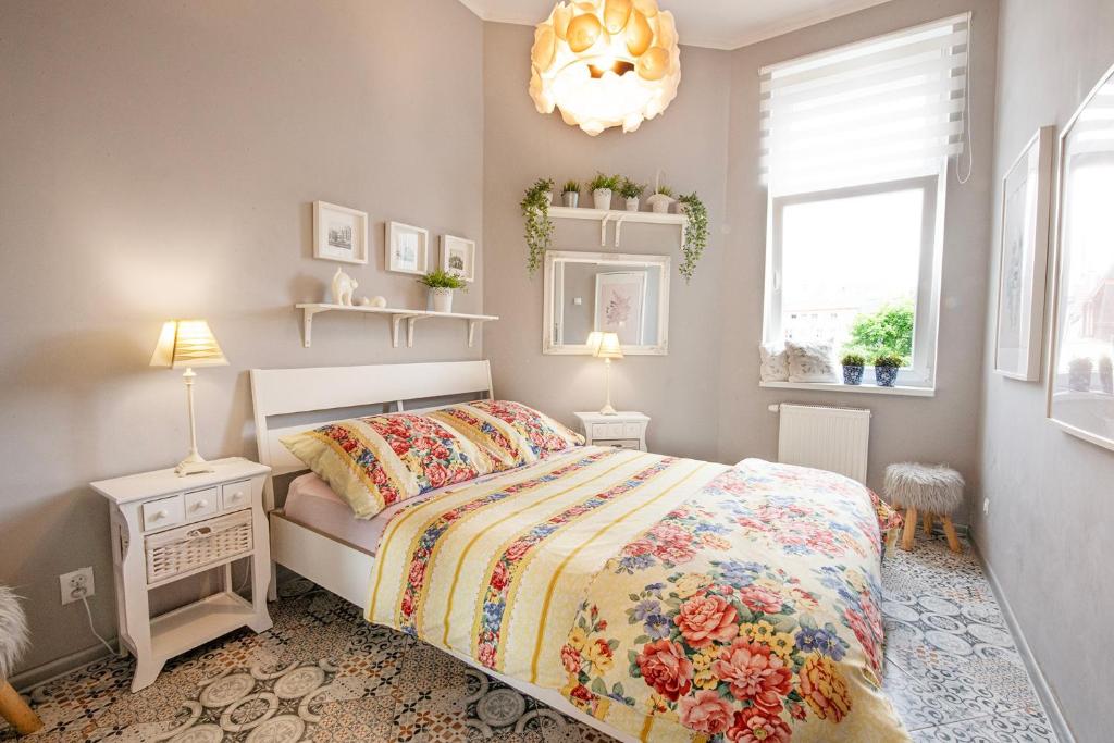 sypialnia z łóżkiem, oknem i żyrandolem w obiekcie Apartament u Olechny 2 w Bydgoszczy