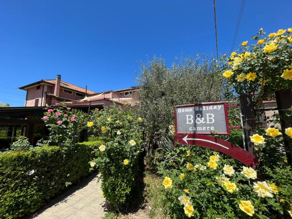 una señal para un hotel con flores delante en B&B Home Holiday Villa delle Acacie agriturismo, en Sala Consilina