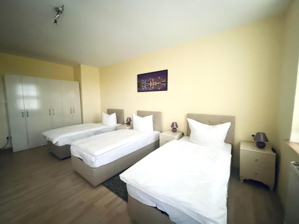 a hotel room with two beds with white sheets at Euphrat Pension in Lichtentanne