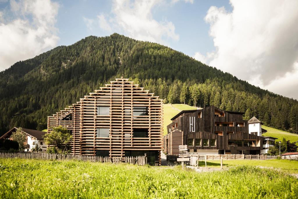 a log house in front of a mountain at Hotel Jaufentalerhof in Racines