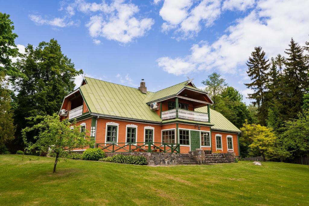 a large house with a green roof on a field at Alaušo Salos - Malinauskų kaimo turizmo sodyba in Sudeikiai