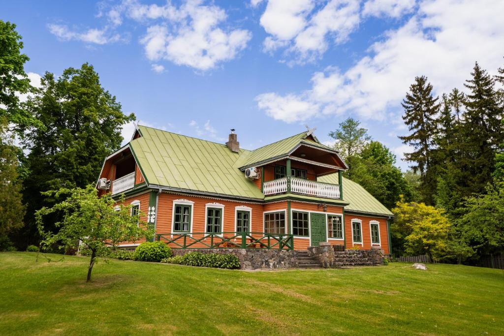 una casa grande con techo verde en un campo en Alaušo Salos - Malinauskų kaimo turizmo sodyba, en Sudeikiai