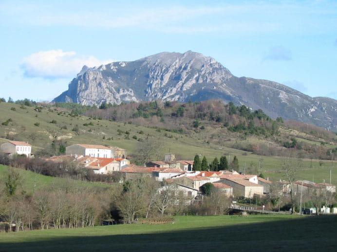 a town in a field with a mountain in the background at Gite de l'école 