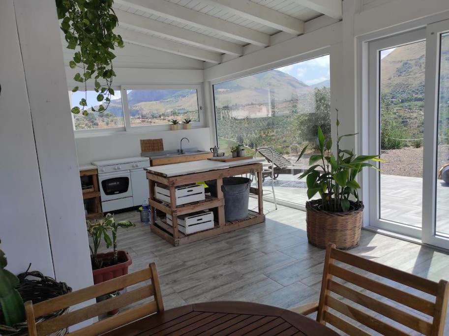 d'une cuisine avec une table, des plantes et des fenêtres. dans l'établissement Casa cardillo tra mare e monti, à Casteldaccia