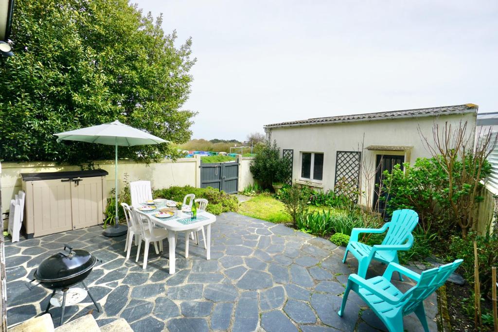 eine Terrasse mit einem Tisch, Stühlen und einem Sonnenschirm in der Unterkunft Le Clos de l'Anse *front de mer* in Ploemeur