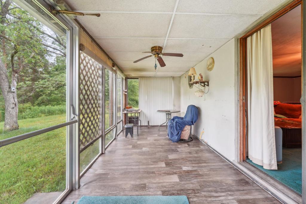 a screened porch with a ceiling fan and a table at Cozy Eldred Getaway - 12 Mi to Rock City Park! in Eldred