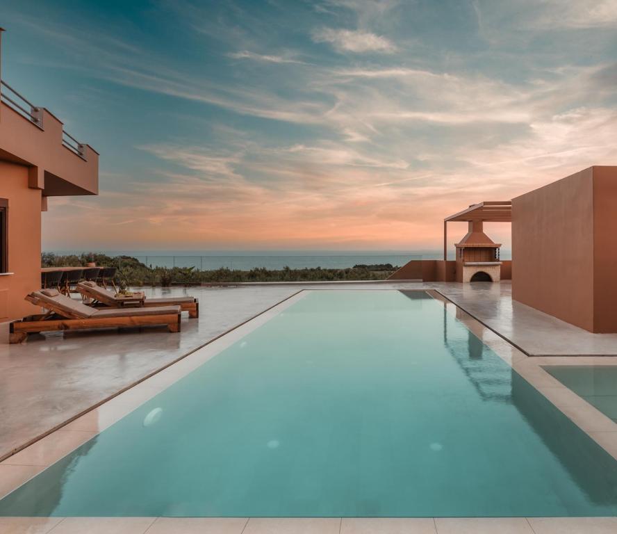 a swimming pool in front of a house with the ocean at Aerope SeaView Villa, a Family Retreat, By ThinkVilla in Koutsounari