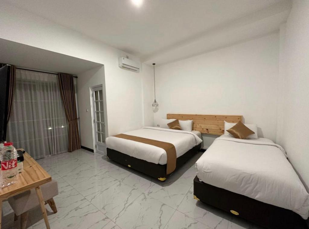 Habitación de hotel con 2 camas y mesa en Omahku Homestay, en Borobudur