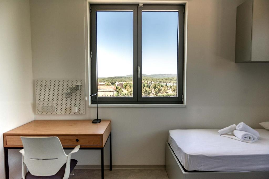 Cette chambre comprend un bureau, un lit et une fenêtre. dans l'établissement Hostel 'SD Palacin', à Šibenik